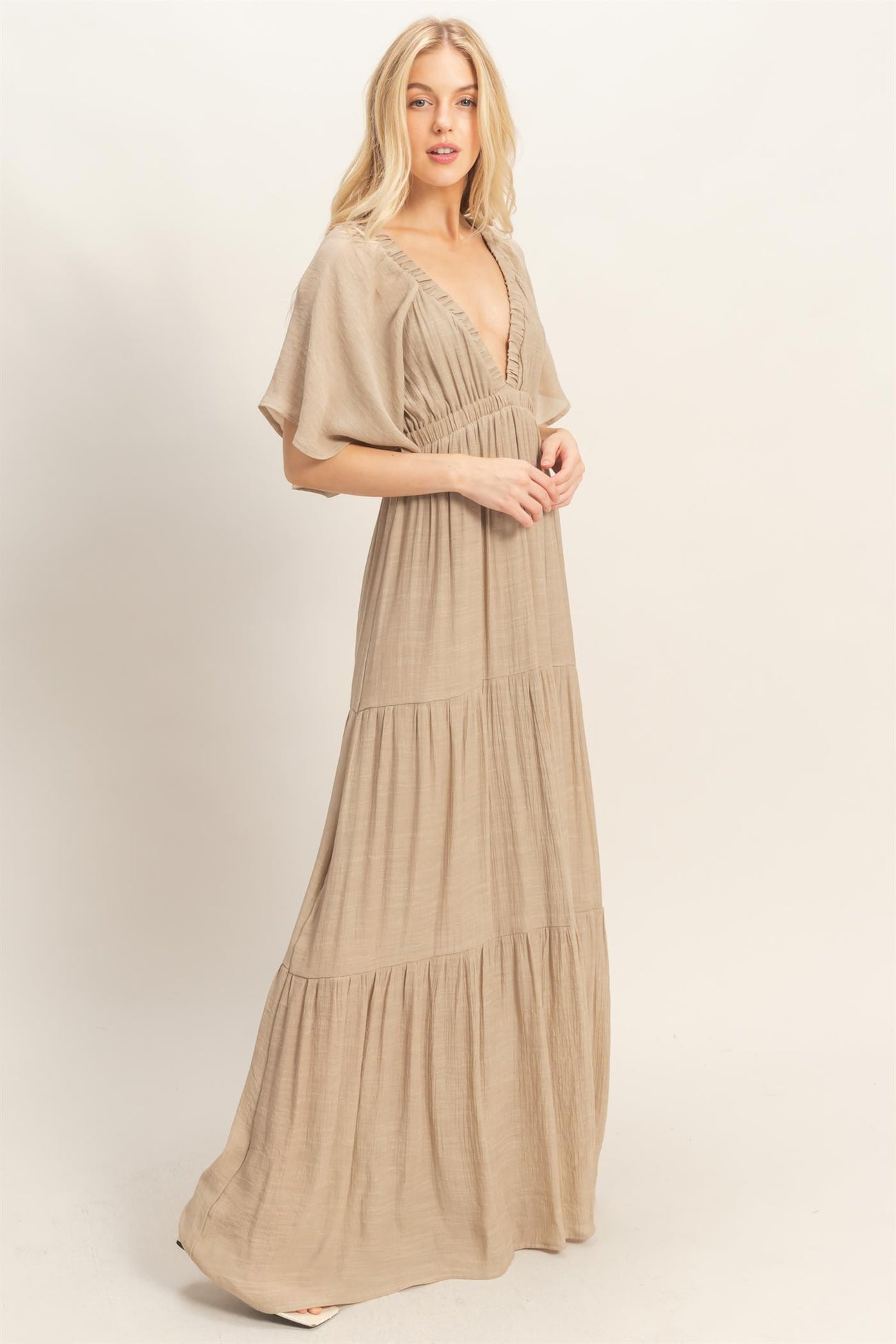 woman wearing a beige maxi dress with a deep v-neck and tiered skirt panels