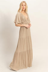 woman wearing a beige maxi dress with a deep v-neck and tiered skirt panels