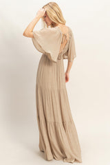 woman wearing a beige maxi dress with a tiered skirt and open back detail