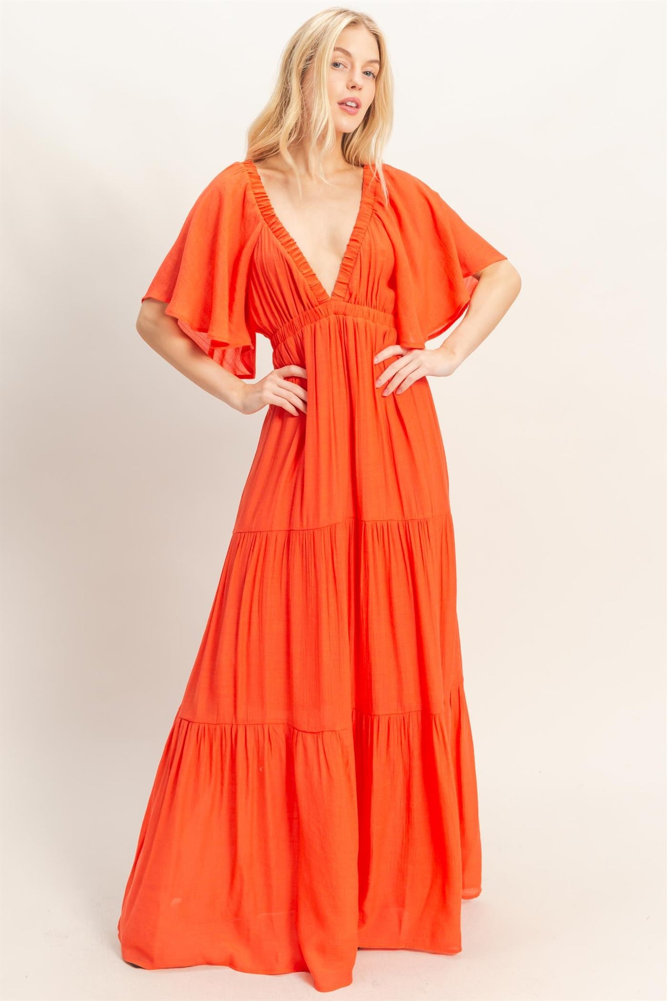 woman wearing a vibrant orange maxi dress with a deep v-neck and flutter sleeves
