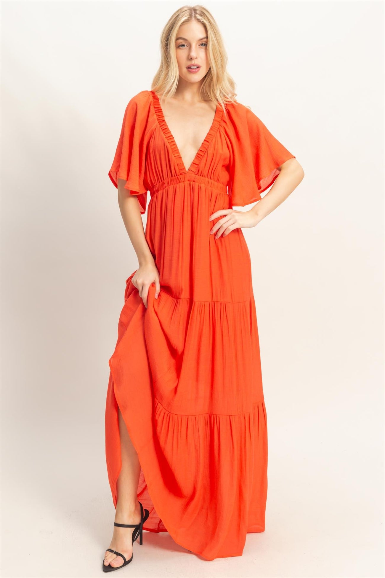 woman wearing a vibrant orange maxi dress with a deep V-neckline and flutter sleeves