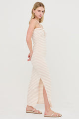 woman wearing a light pink striped maxi dress with a side slit and adjustable spaghetti straps
