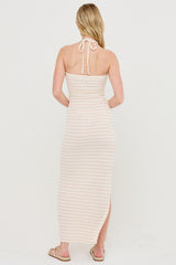 woman wearing a light pink striped maxi dress with a halter neckline and a thigh-high slit
