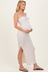 woman wearing a light pink and white striped maternity maxi dress with a side slit and holding her baby bump