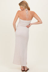 woman wearing a light pink striped maternity maxi dress with a halter neck and back tie detail