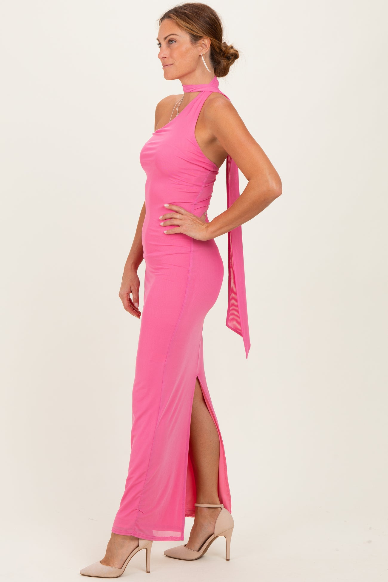 woman wearing a hot pink halter neck gown with a side slit and a flowing back tie detail
