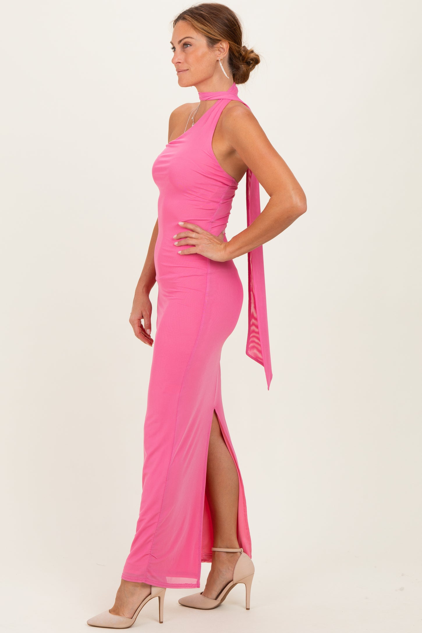 woman wearing a hot pink halter neck gown with a side slit and a flowing back tie detail