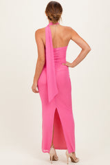 woman wearing a pink halter neck maxi dress with a slit at the back and a flowing scarf detail