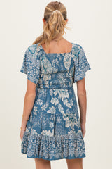 woman wearing a blue floral maternity dress with short flutter sleeves and a ruffled hem, shown from the back