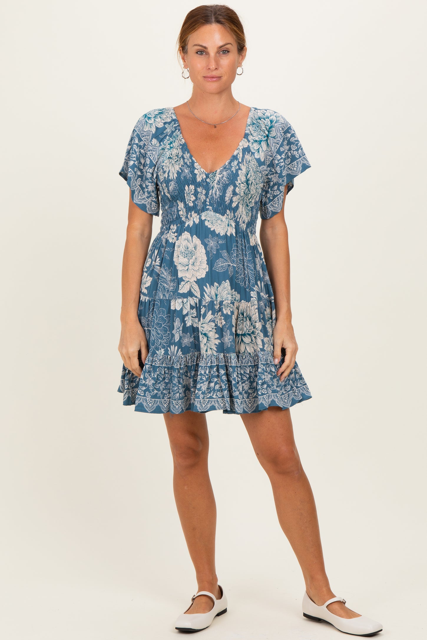 woman wearing a blue floral short sleeve dress with a v-neck and ruffled hem