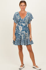 woman wearing a blue floral short sleeve dress with a v-neck and ruffled hem