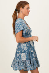 woman wearing a blue floral print short sleeve dress with a ruffled hem, posing in profile