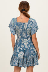 woman wearing a blue floral print dress with short sleeves and a tiered ruffle hem, viewed from the back