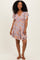 woman wearing a floral print v-neck short sleeve dress with a flowy skirt and smiling at the camera