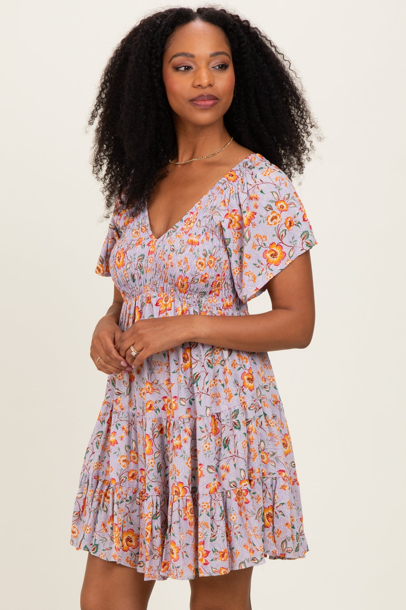 woman wearing a floral print lilac dress with short flutter sleeves and a tiered skirt