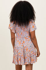 woman wearing a floral print short dress with a smocked back and ruffled hem standing with her back to the camera