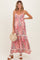 woman wearing a floral maternity maxi dress with adjustable straps and a baby bump, holding a woven bag