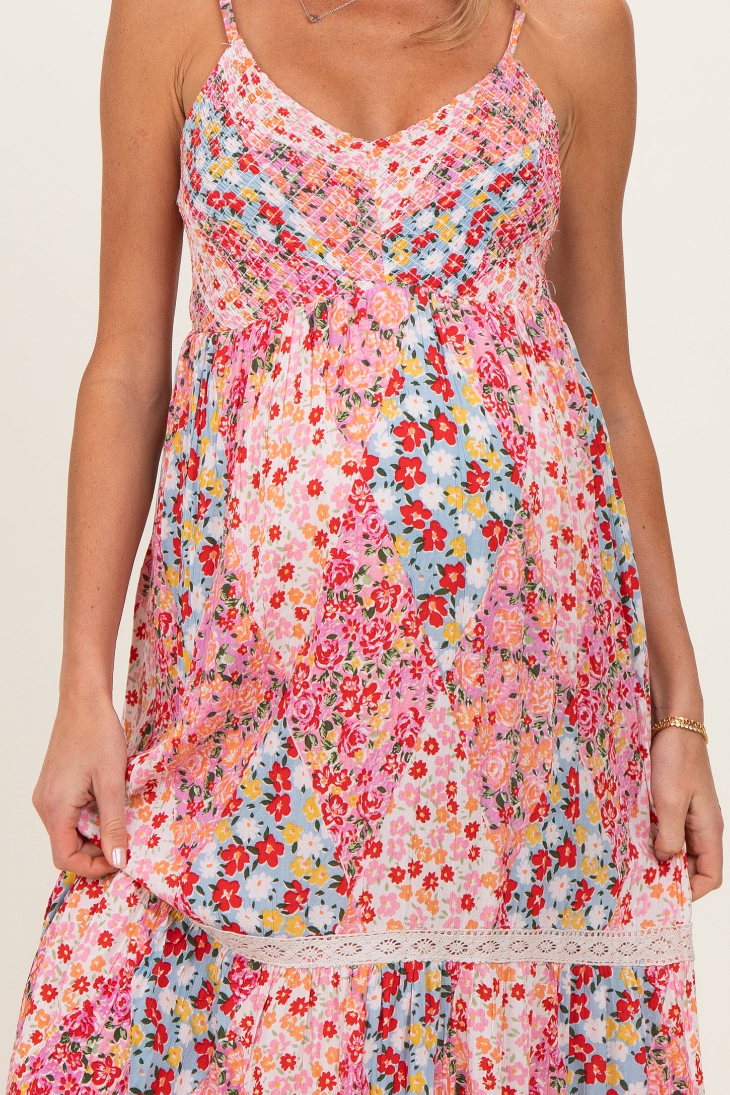 woman wearing a colorful floral maternity dress with adjustable straps and a gathered baby bump