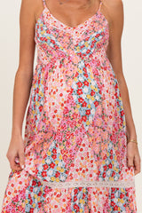 woman wearing a colorful floral maternity dress with adjustable straps and a gathered baby bump