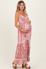 woman wearing a pink floral maternity maxi dress and holding her baby bump