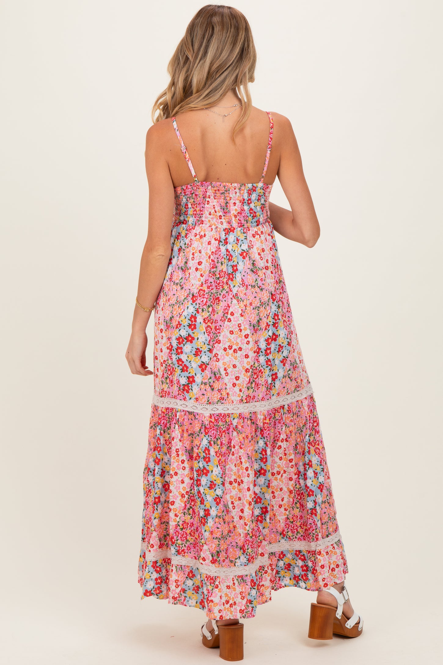 woman wearing a colorful floral print maternity maxi dress with spaghetti straps and tiered skirt from the back