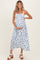 woman wearing a white floral maternity dress with blue flowers, holding her baby bump