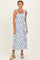 woman wearing a white maxi dress with blue floral print and tie shoulder straps