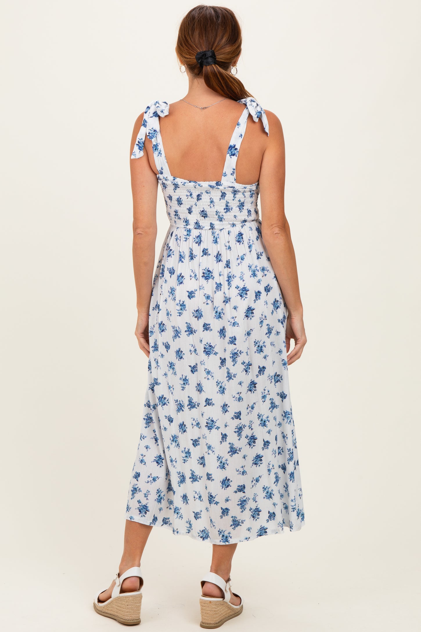 woman wearing a blue and white floral maxi dress with tie shoulder straps and a smocked back