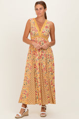woman wearing a yellow floral maxi dress with a v-neck and empire waist, standing and smiling in wedge sandals