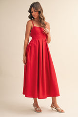 woman wearing a red midi dress with spaghetti straps and box pleats, styled with strappy heels