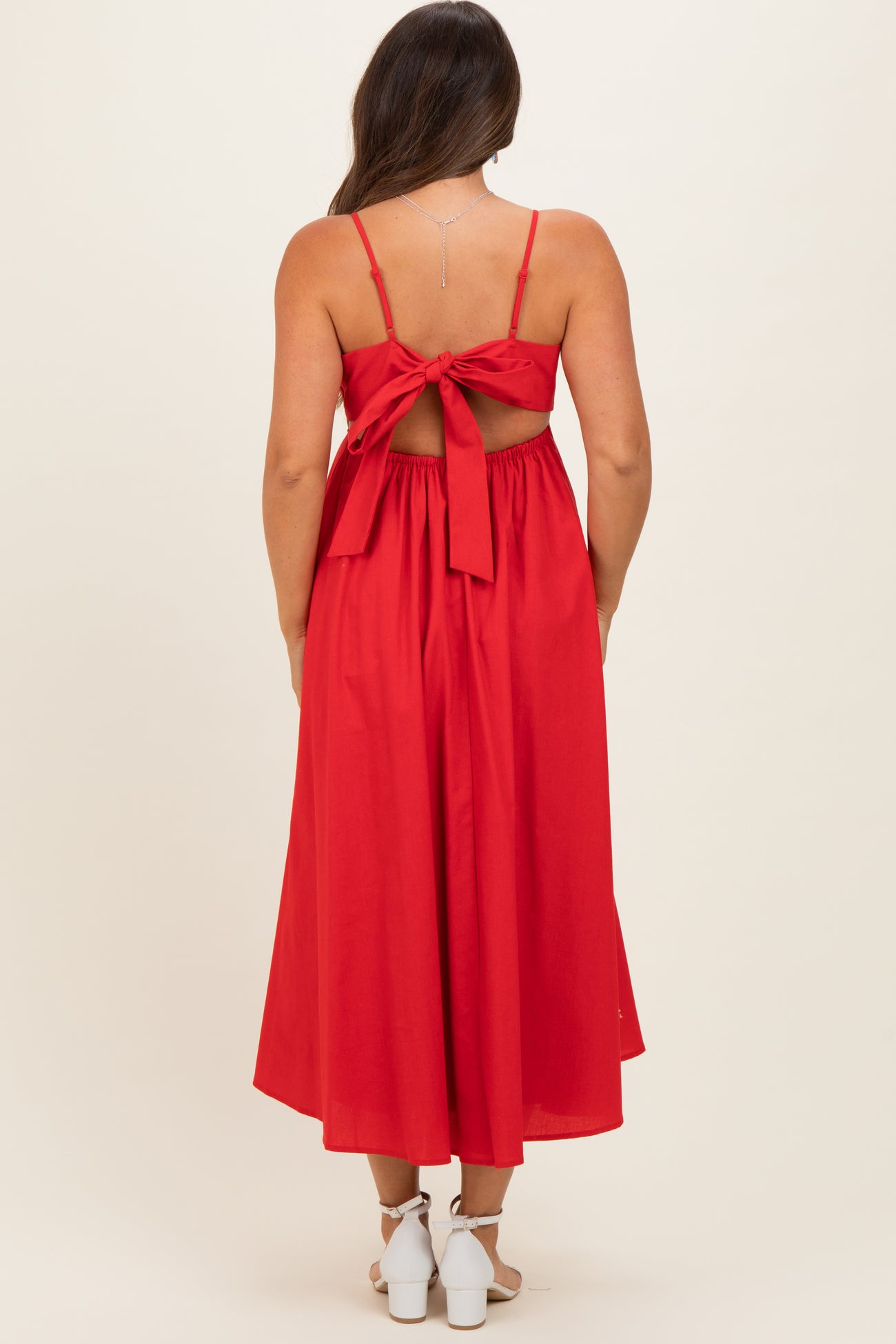 woman wearing a red maternity maxi dress with a tied back detail and a flowy silhouette