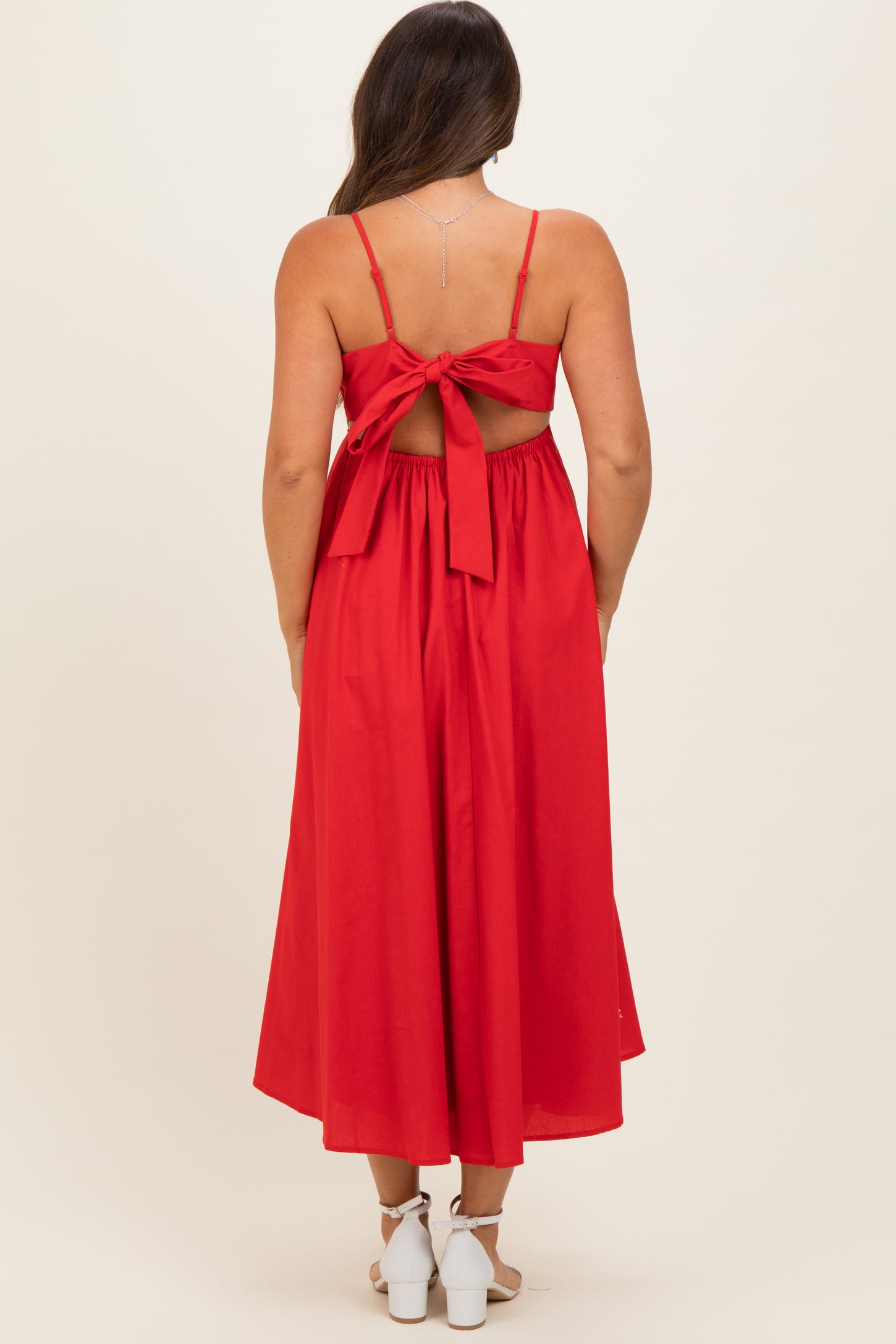 woman wearing a red maternity maxi dress with a tied back detail and a flowy silhouette