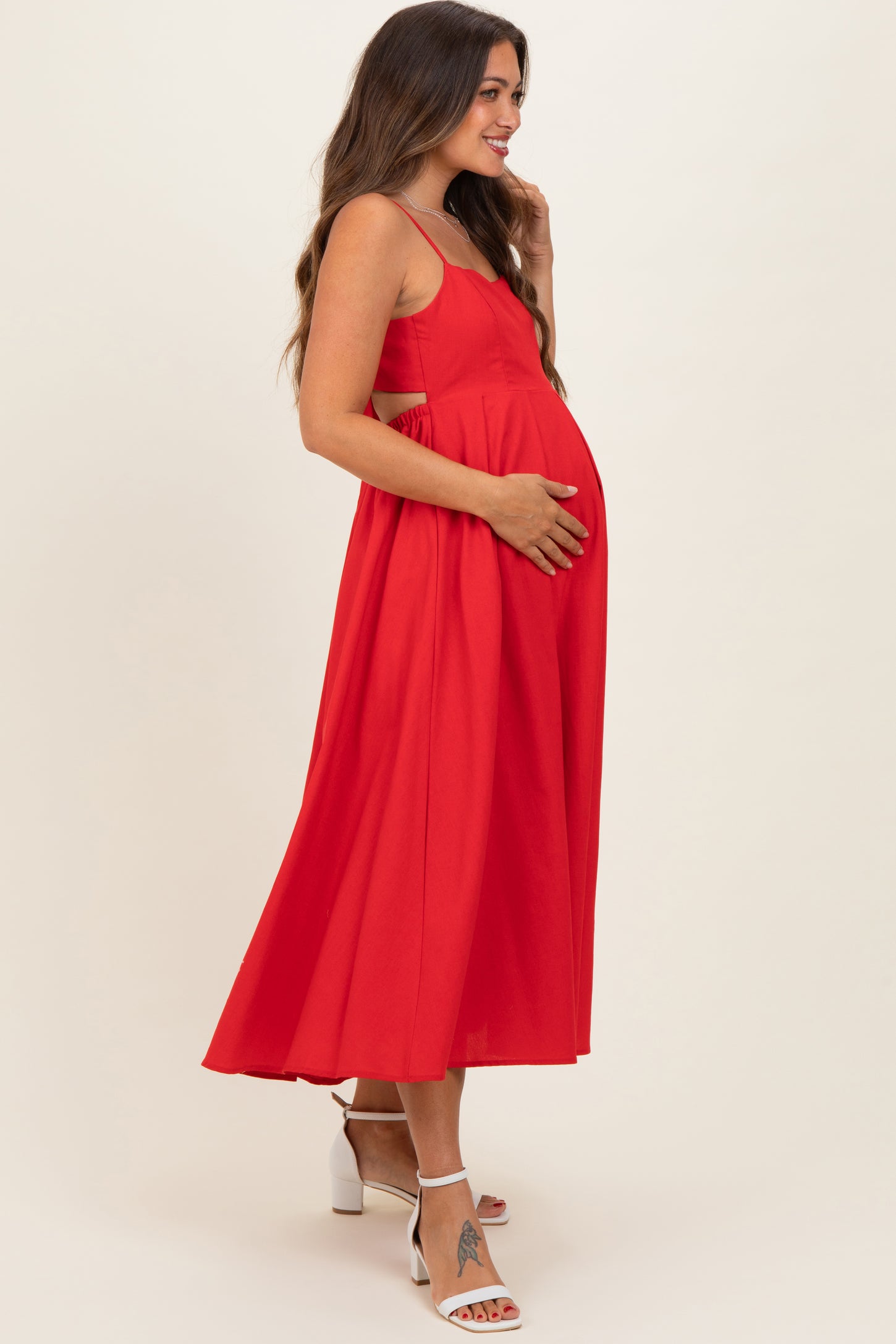 woman wearing a red maternity dress with a flowing skirt and holding her baby bump
