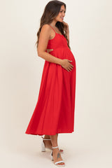 woman wearing a red maternity dress with a flowing skirt and holding her baby bump