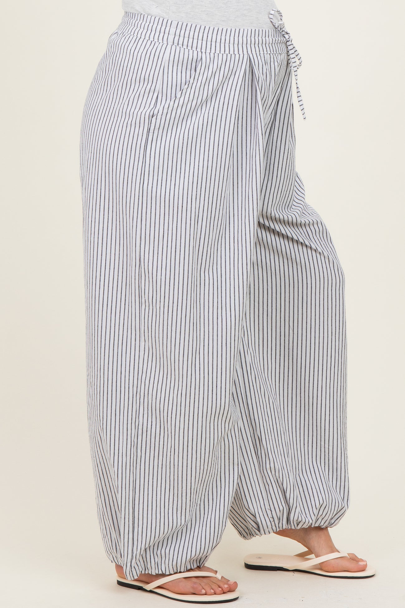 woman wearing gray and white striped maternity pants with an elastic waistband and drawstring