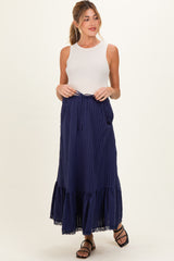 woman wearing a white sleeveless top and a navy blue striped maternity maxi skirt with a tie waist and lace hem