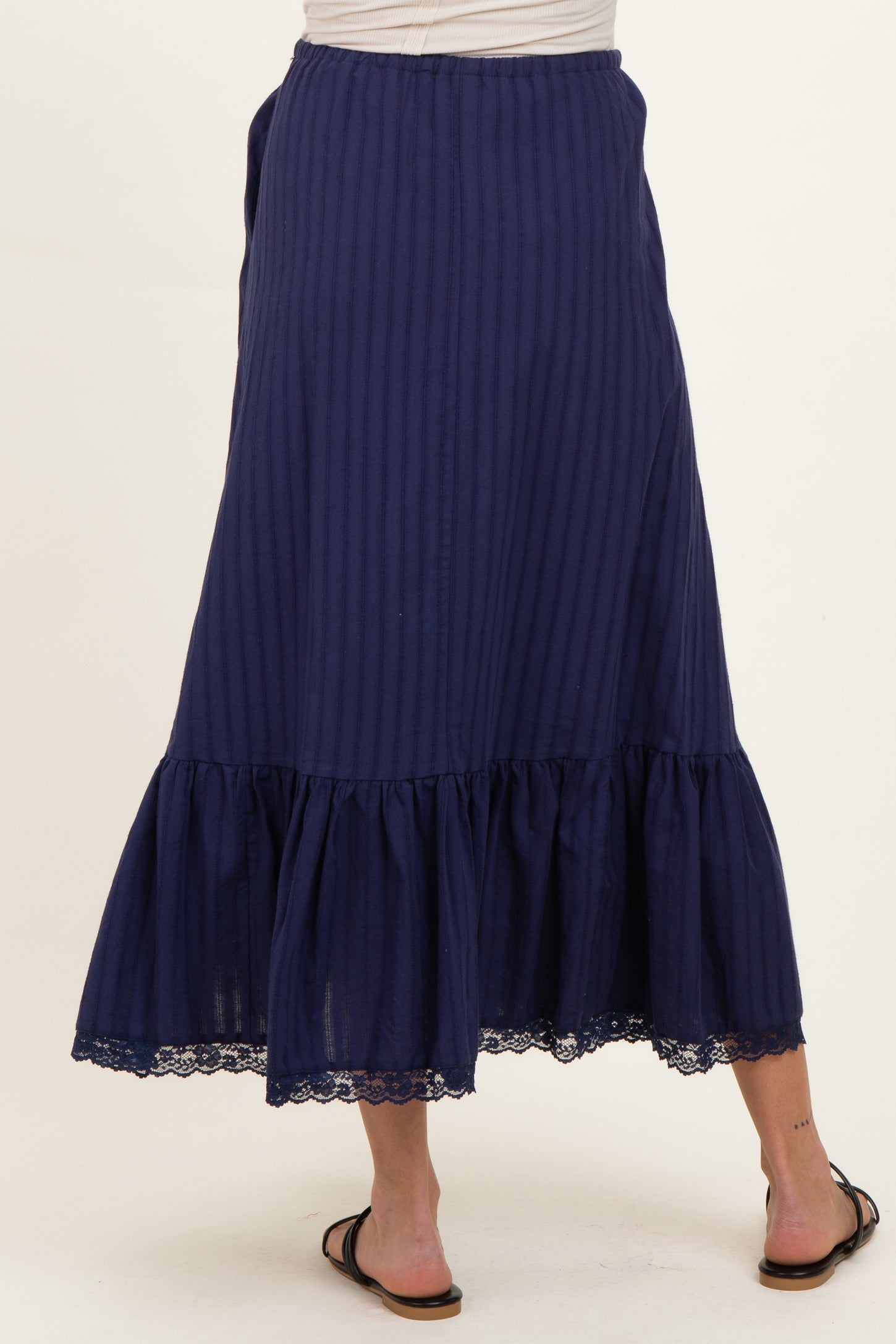 woman wearing a navy blue maternity maxi skirt with a ruffled hem and lace detailing on the bottom