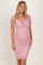 woman wearing a pink polka dot fitted dress with short puff sleeves and a tie detail at the neckline
