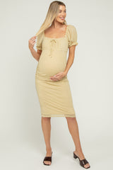 woman wearing a yellow polka dot maternity dress with puff sleeves, showing her baby bump and smiling