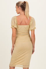 woman wearing a gold polka dot maternity dress with puff sleeves, showing a fitted silhouette and a low square back