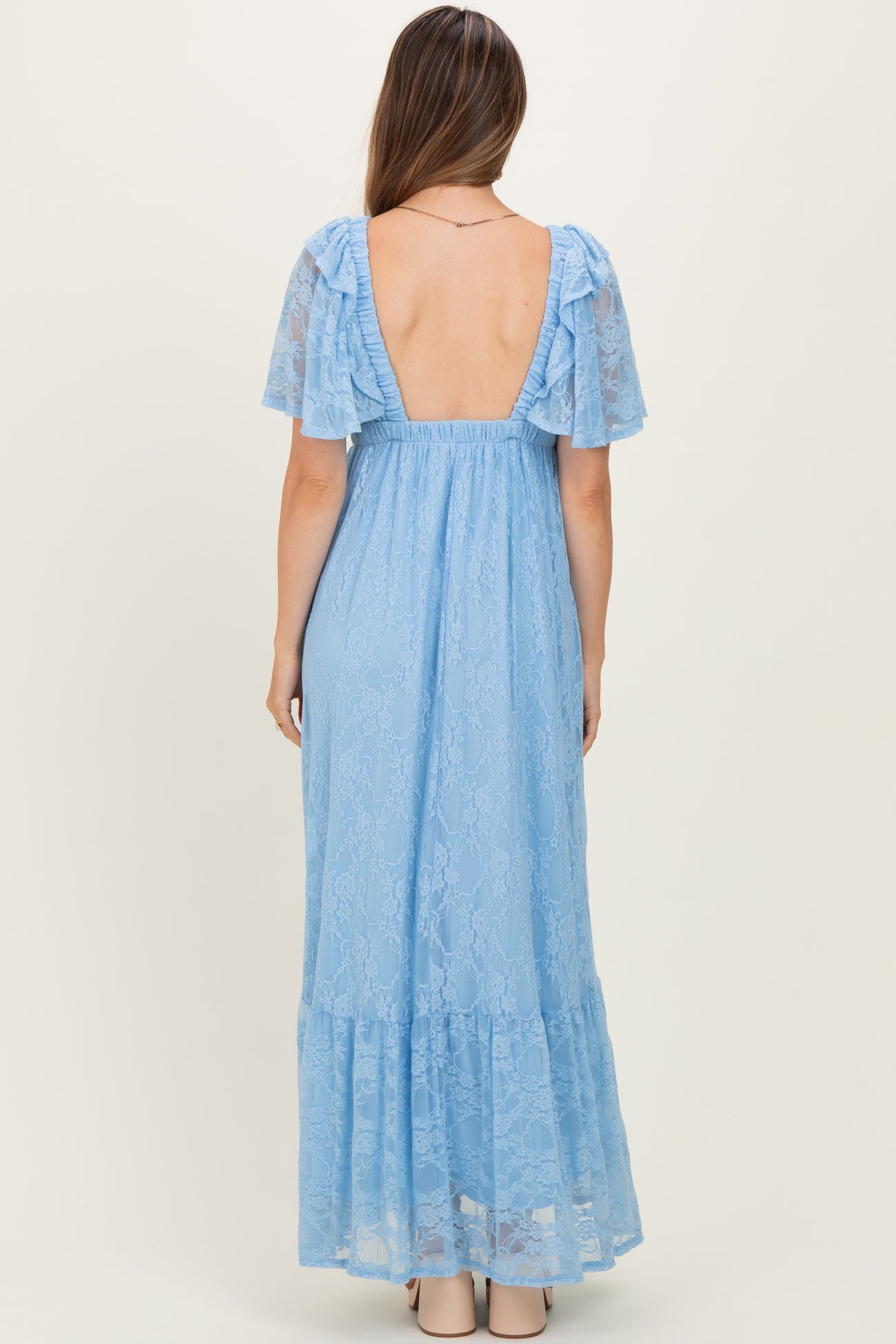 woman wearing a light blue lace maternity maxi dress with short flutter sleeves and a backless design
