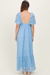 woman wearing a light blue lace maternity maxi dress with short flutter sleeves and a backless design