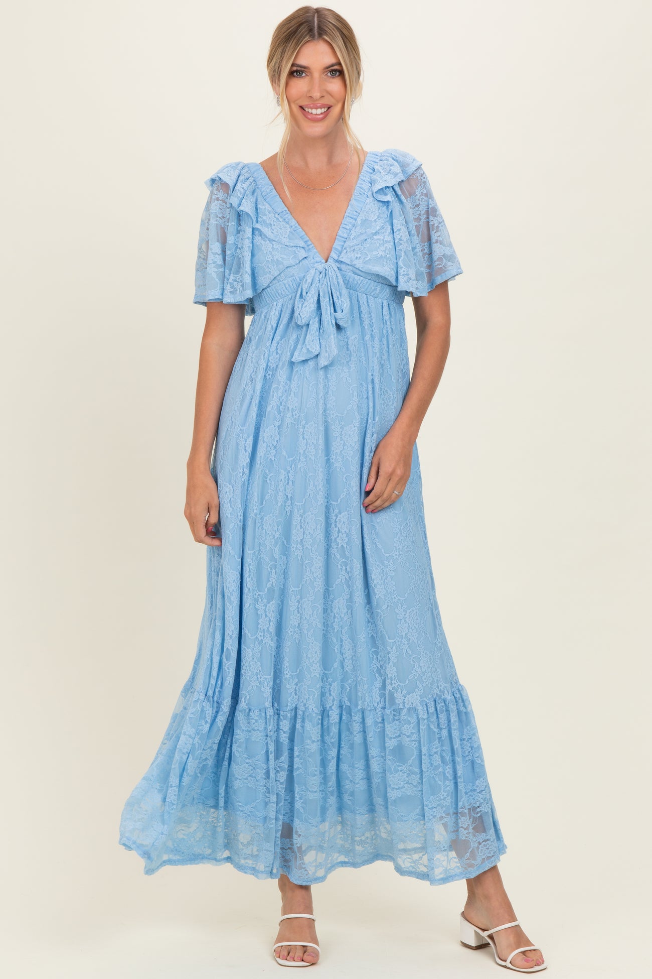 woman wearing a light blue lace maxi dress with short ruffle sleeves and a bow detail at the neckline