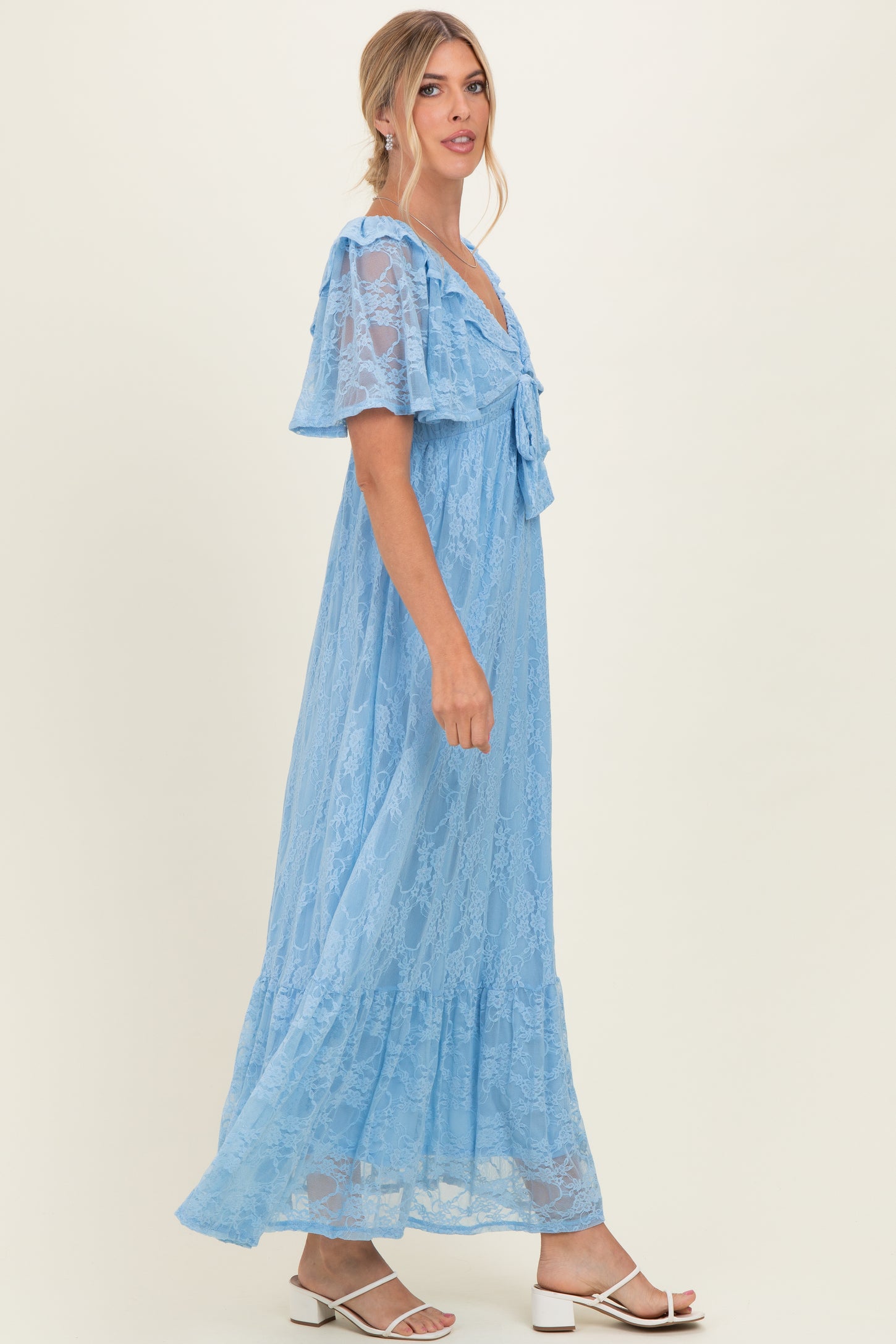 woman wearing a light blue lace maxi dress with short flutter sleeves and a tied neckline