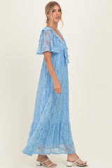 woman wearing a light blue lace maxi dress with short flutter sleeves and a tied neckline