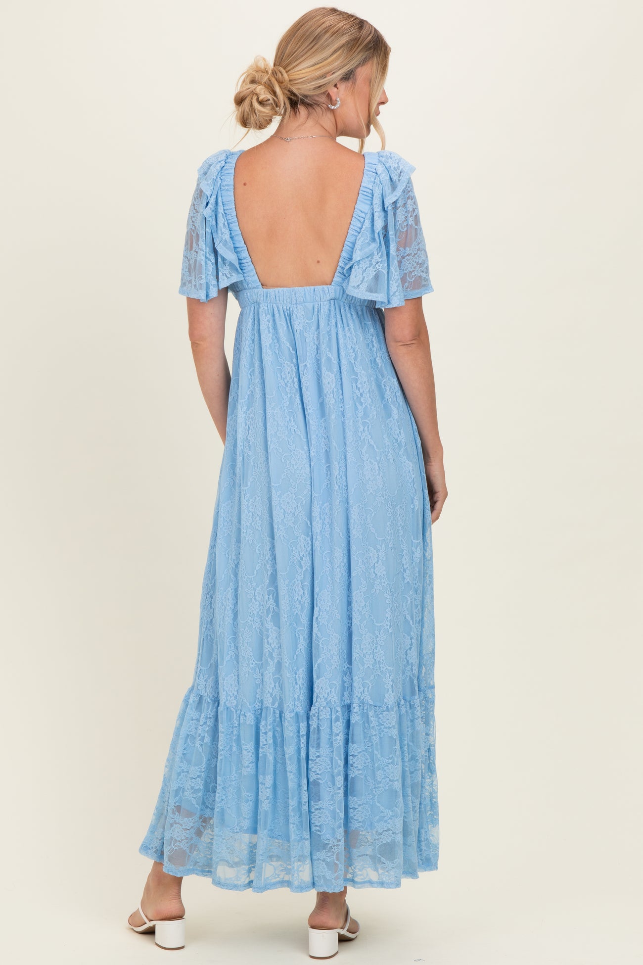woman wearing a light blue lace maxi dress with short ruffled sleeves and an open back