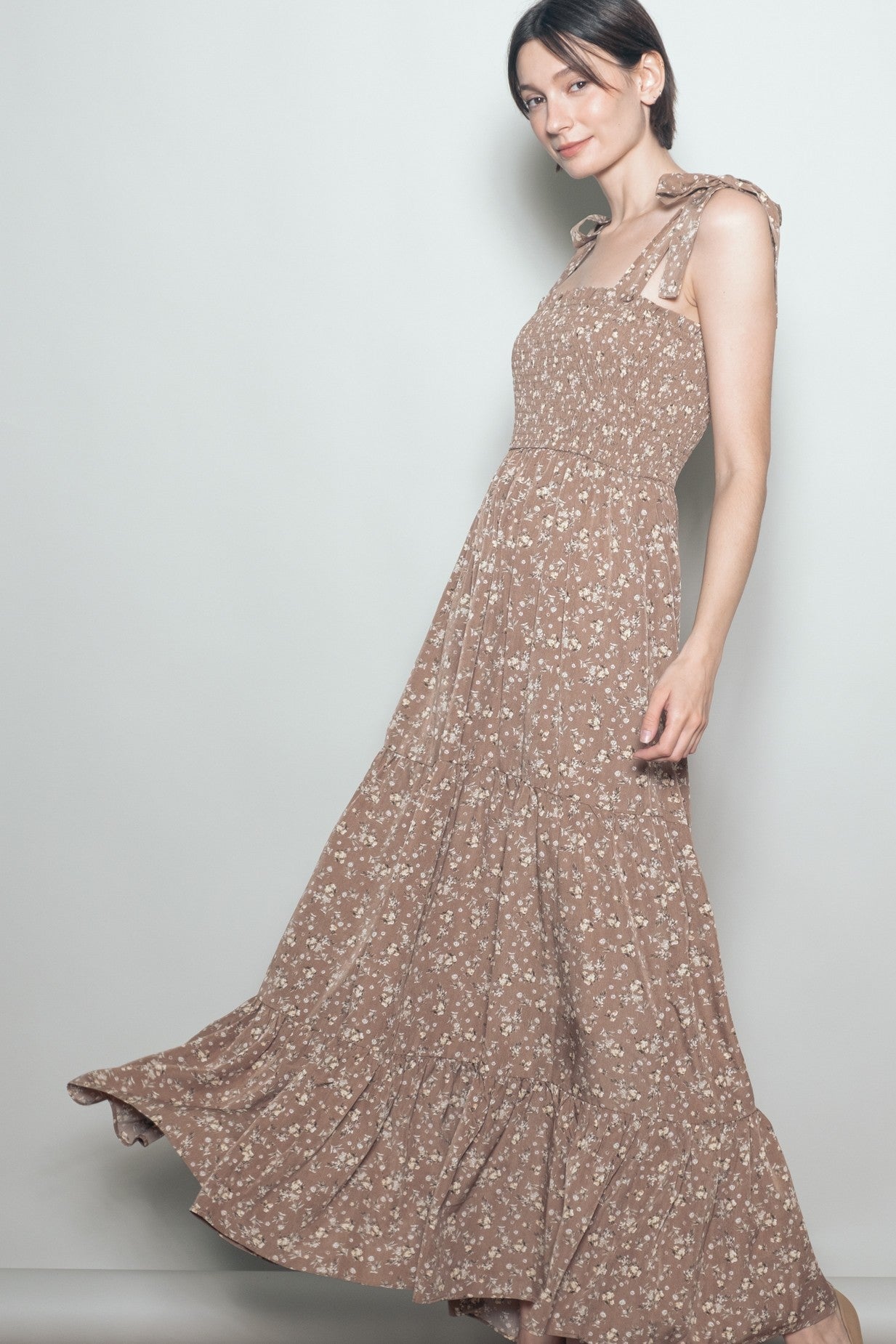 woman wearing a brown floral maxi dress with tie straps and a flowy skirt
