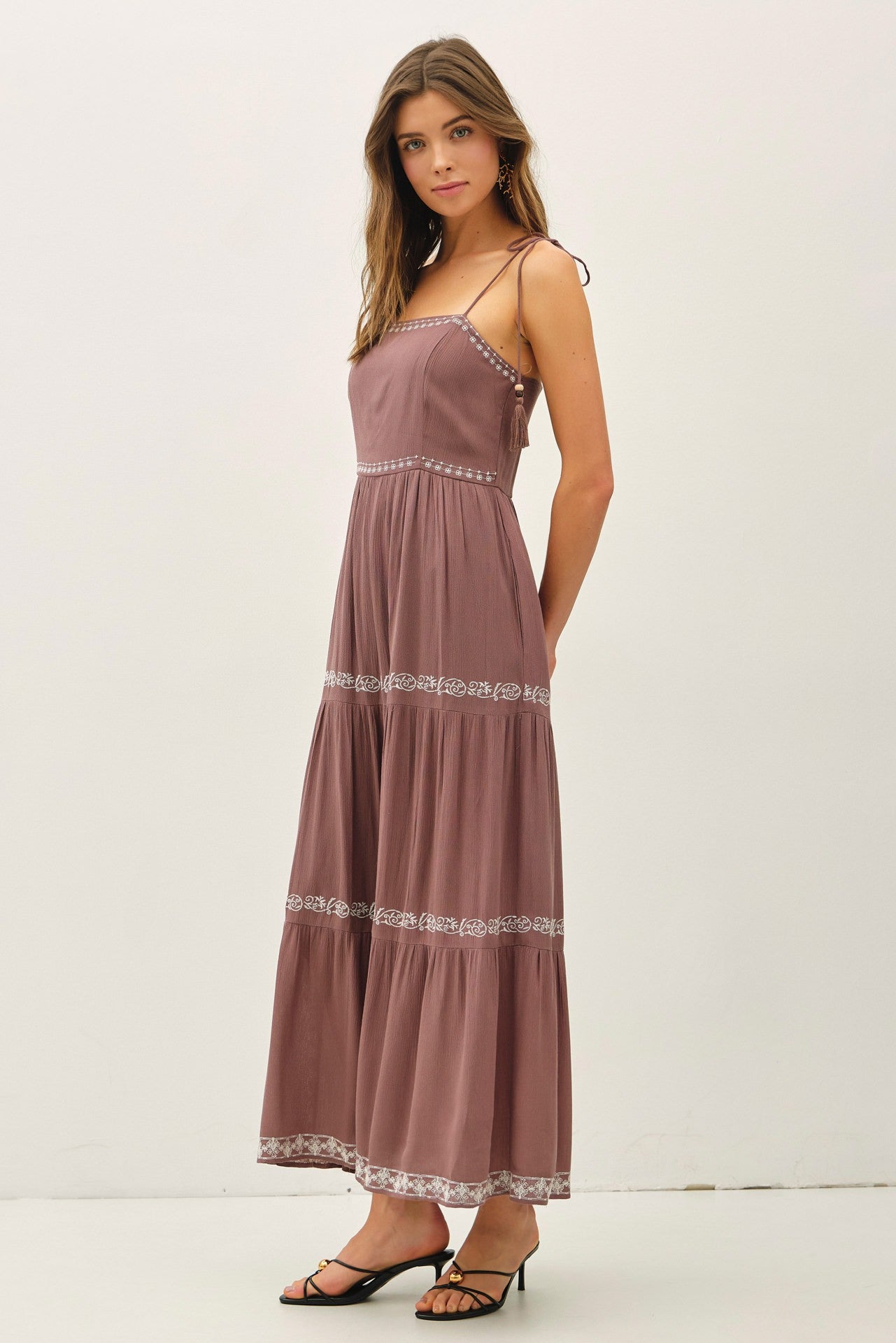 woman wearing a mauve maxi dress with spaghetti straps and embroidered detailing