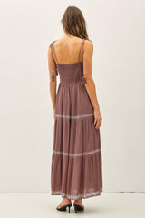woman wearing a mauve maxi dress with a smocked bodice and tassel straps, showing the back view