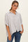 woman wearing a striped button-up shirt with rolled sleeves and a loose fit, paired with blue jeans